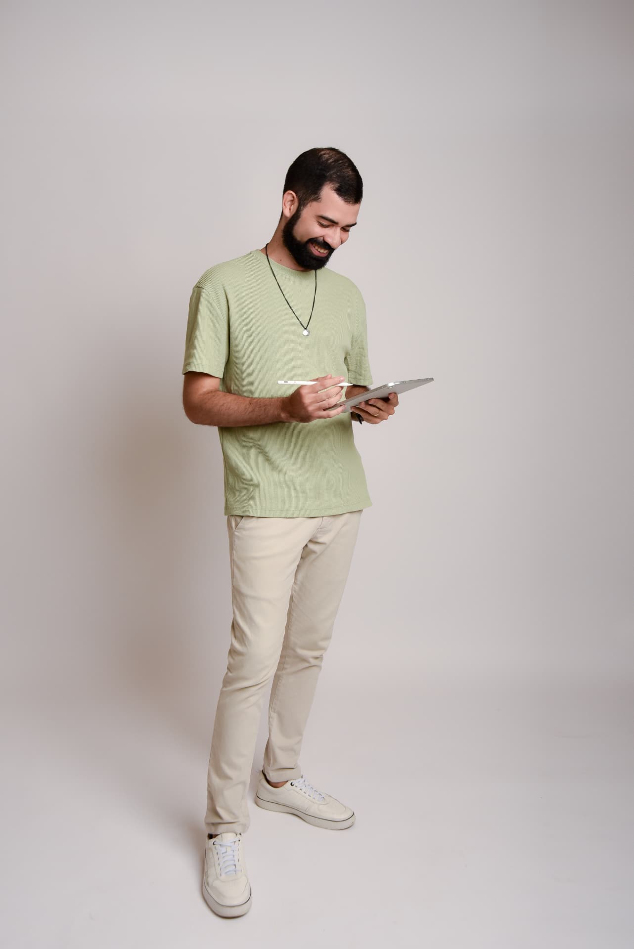 Ítalo Melo em pé, revisando dados em um tablet